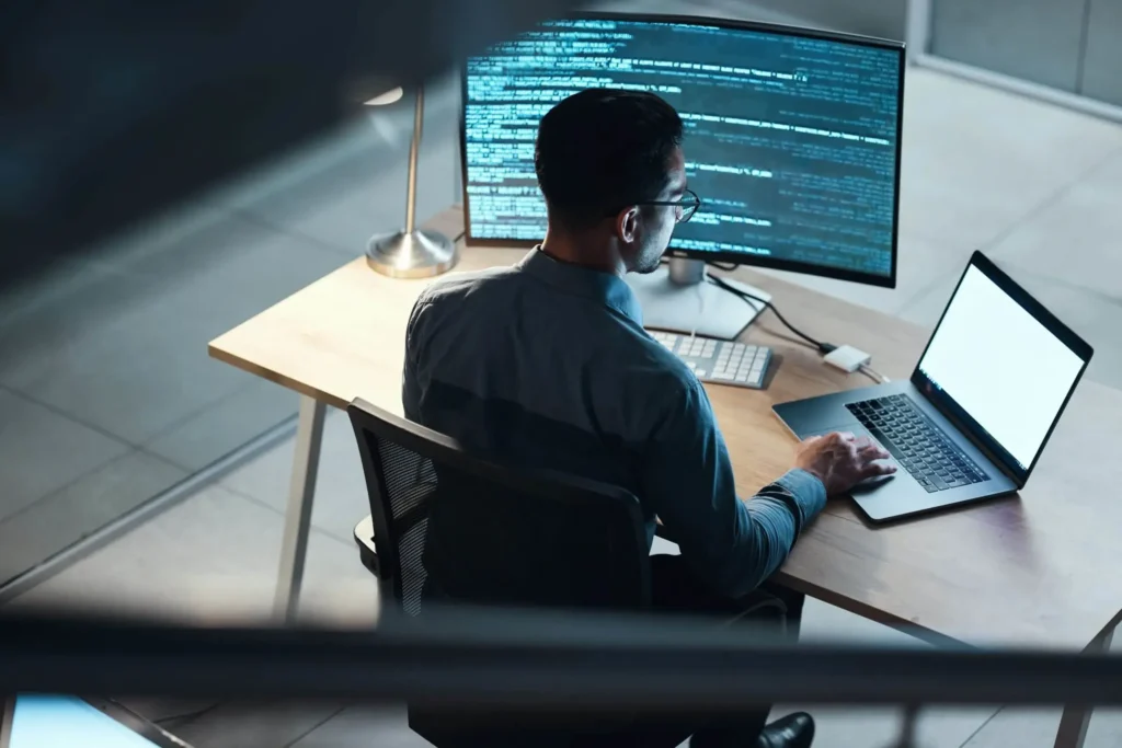 Person working on a computer with code at night, representing dedicated cybersecurity solutions.